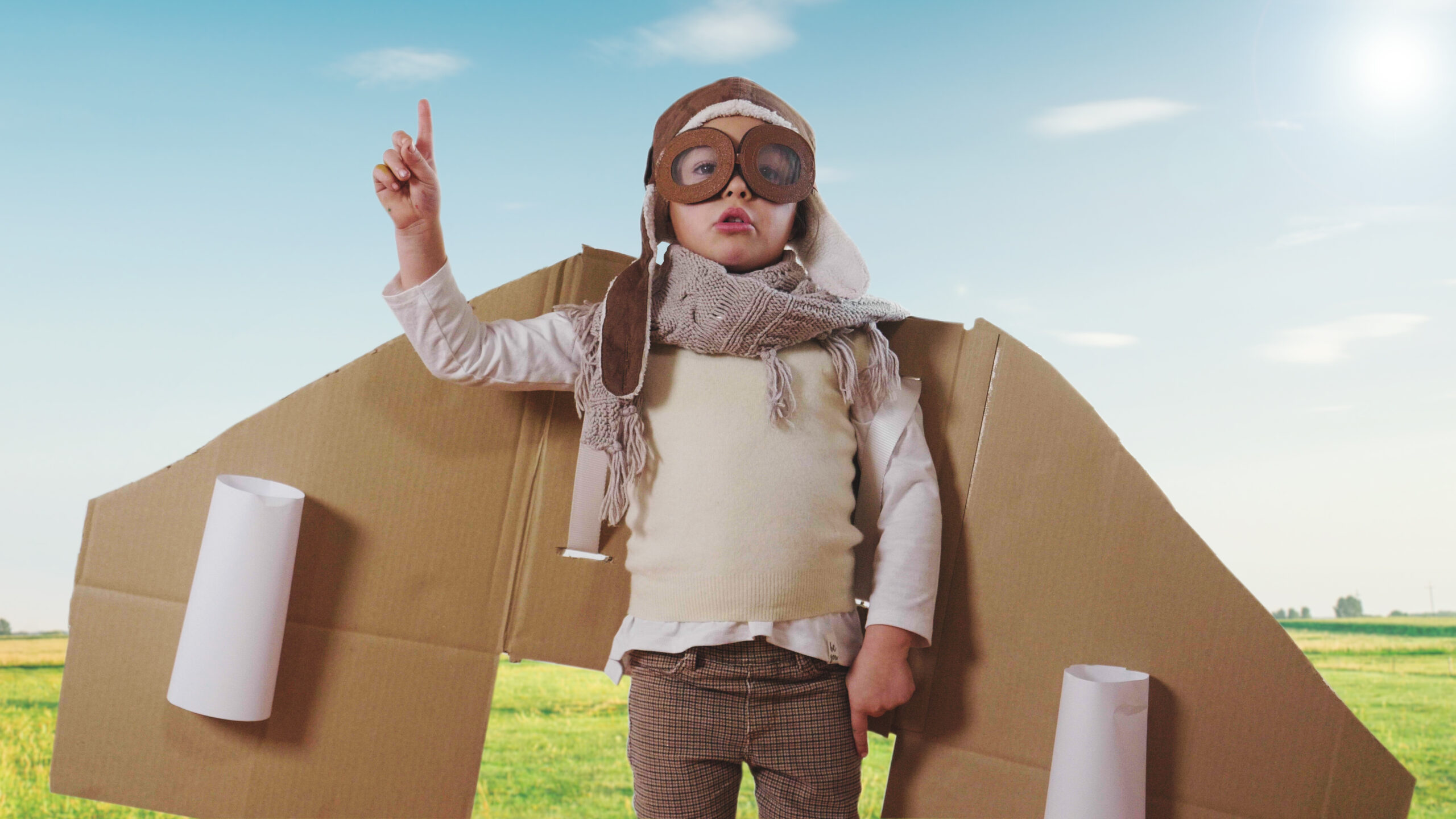 Portrait of a girl, dressed as a pilot or aviator with a hat and glasses, smiles looking at the camera, she dreams with open eyes and thinks about the future.